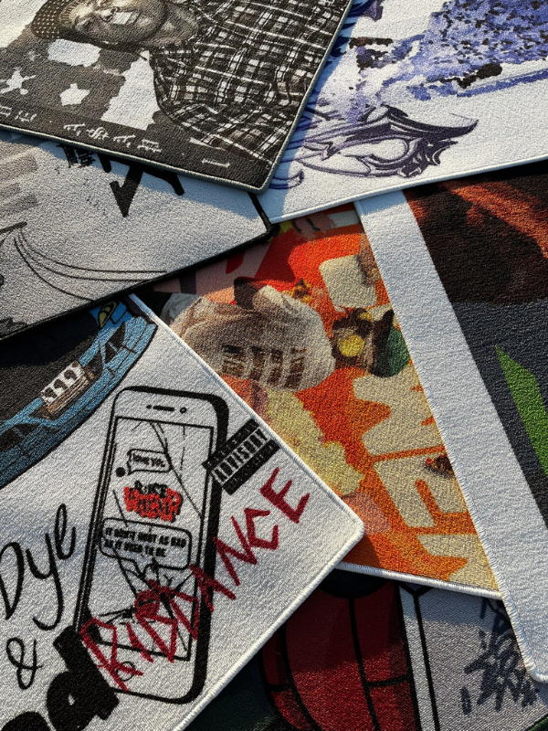 Rugs – stacked, mixed covers Close view of overlapped album-inspired rugs, partial covers visible including Juice, Flower Boy, A$AP, GNX, Blonde, DOOM, JEFFERY