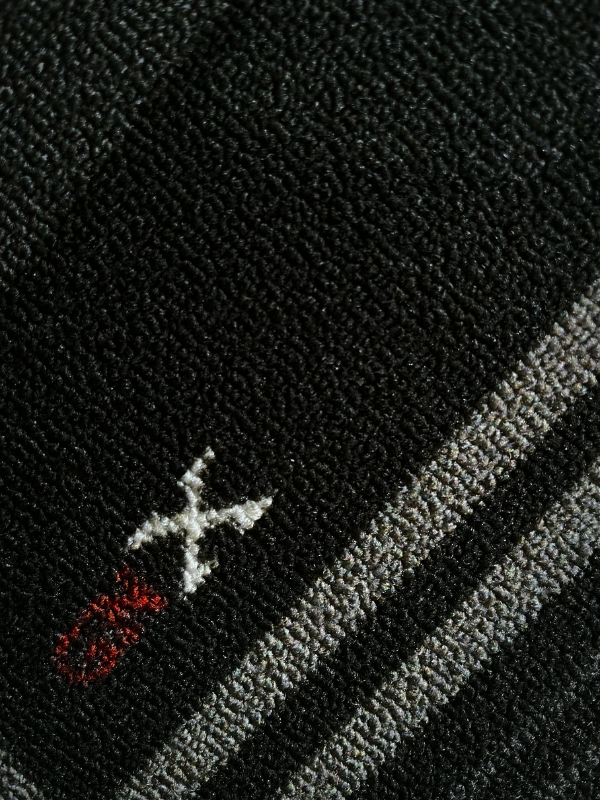 GNX rug close-up highlighting the only red GNX logo element against the pixel-style weave