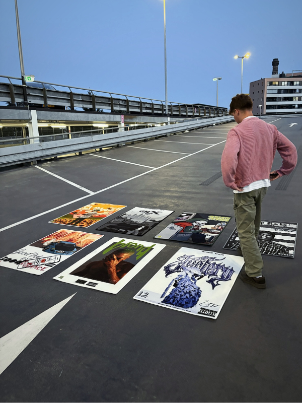 New collection – parking lot layout New collection rugs laid out in a 4×3 grid on a parking lot while a person stands/walks alongside